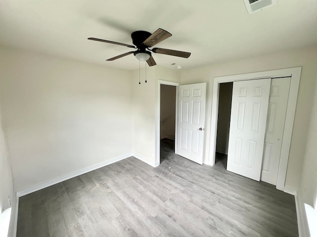 unfurnished bedroom featuring hardwood / wood-style flooring, ceiling fan, and a closet