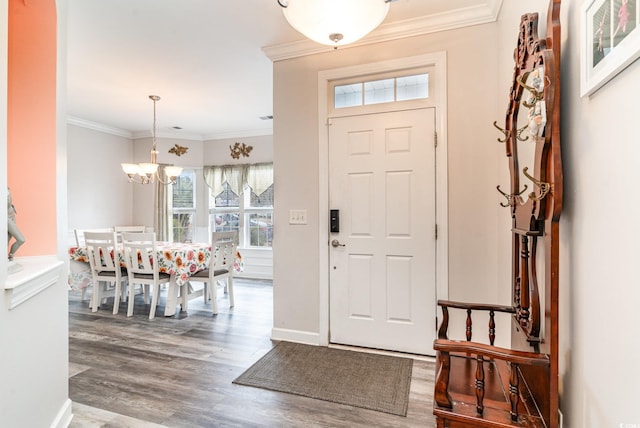 foyer entrance featuring crown molding, wood-type flooring, and an inviting chandelier