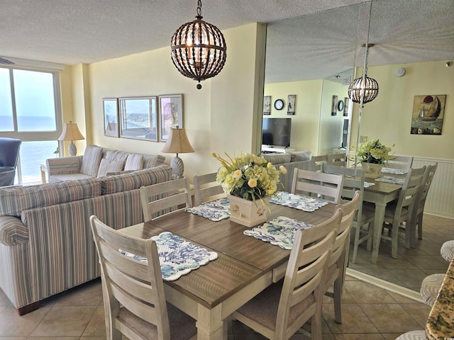 dining space featuring a textured ceiling, tile patterned floors, and a chandelier