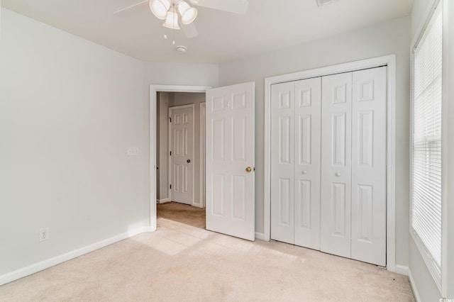 unfurnished bedroom featuring ceiling fan, a closet, light colored carpet, and multiple windows