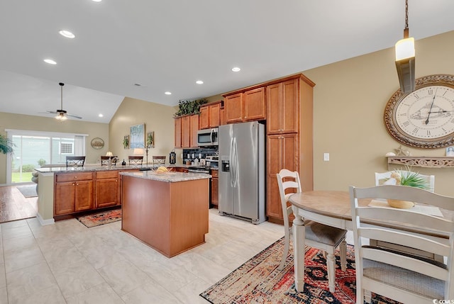 kitchen with stainless steel appliances, lofted ceiling, ceiling fan, and a kitchen island