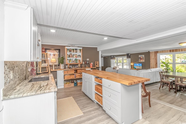 kitchen featuring light hardwood / wood-style flooring, plenty of natural light, white cabinetry, and butcher block counters