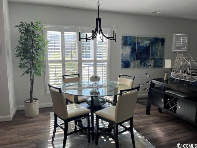 dining space featuring baseboards, an inviting chandelier, and wood finished floors