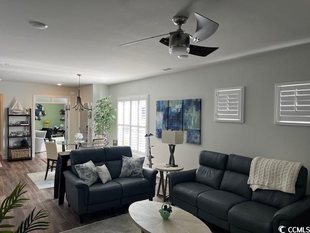 living room featuring ceiling fan with notable chandelier and wood finished floors