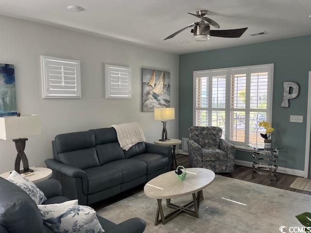 living room with visible vents, wood finished floors, baseboards, and ceiling fan