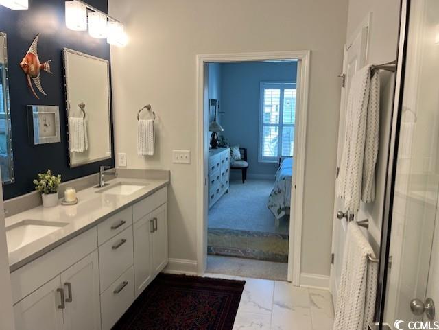 full bath with baseboards, marble finish floor, and a sink