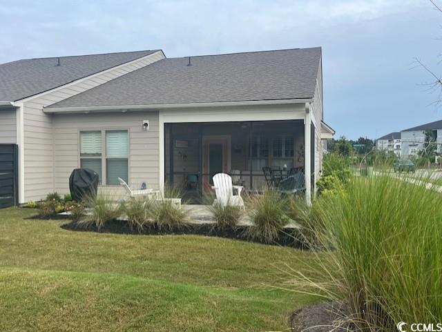back of property with a yard and a shingled roof