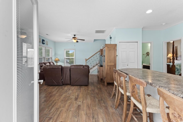 dining space featuring stairway, wood finished floors, a ceiling fan, visible vents, and ornamental molding