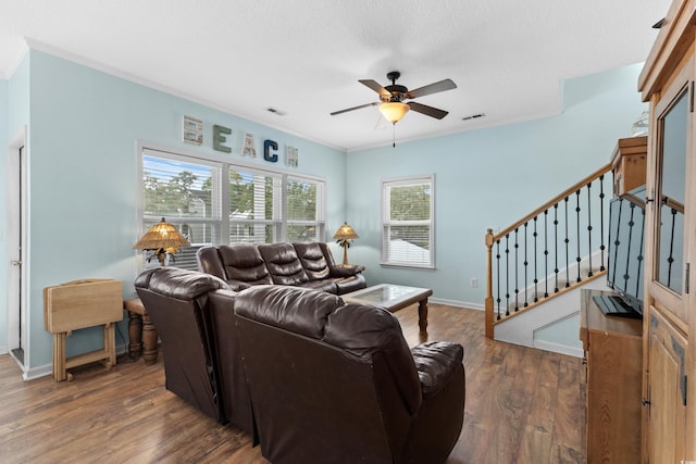 living room with stairway, wood finished floors, baseboards, visible vents, and ceiling fan