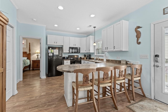 kitchen featuring a peninsula, a sink, black appliances, white cabinets, and dark countertops