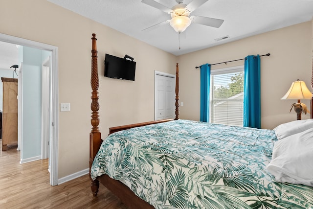 bedroom featuring visible vents, a ceiling fan, wood finished floors, a closet, and baseboards