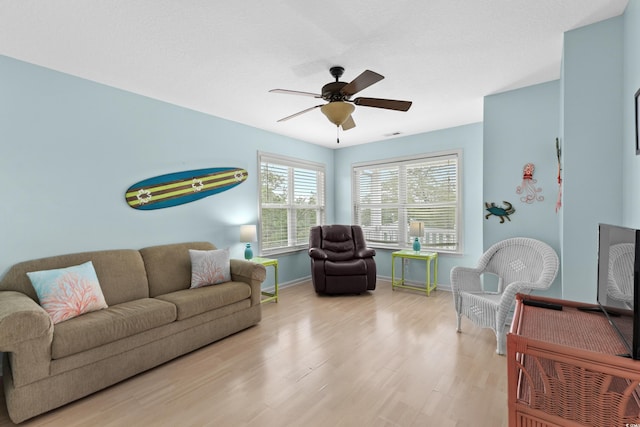 living area featuring ceiling fan, baseboards, and wood finished floors