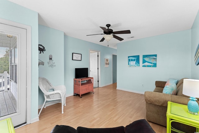 living room featuring visible vents, baseboards, light wood-style floors, and ceiling fan