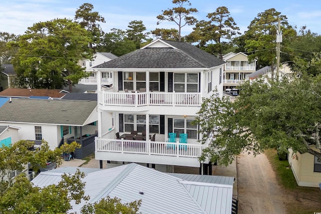 rear view of house featuring a shingled roof and a sunroom