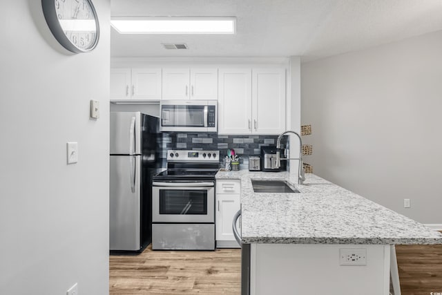 kitchen with stainless steel appliances, sink, light wood-type flooring, and white cabinets