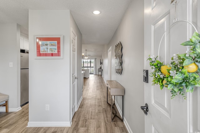 hallway featuring a textured ceiling and light hardwood / wood-style flooring