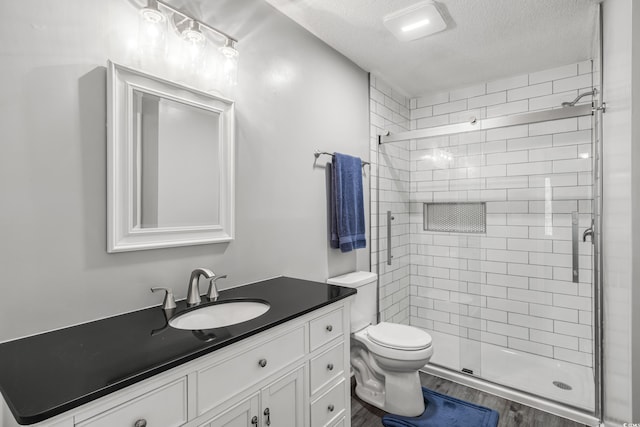 bathroom featuring vanity, toilet, wood-type flooring, and a shower with door