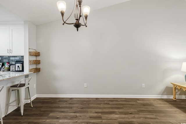 dining area featuring vaulted ceiling, a notable chandelier, and dark hardwood / wood-style flooring