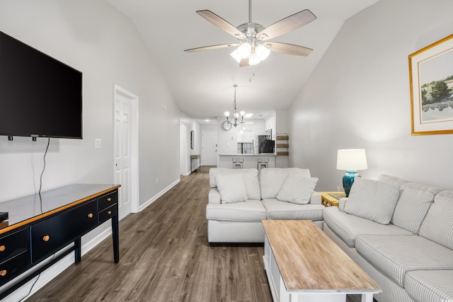 living room featuring ceiling fan with notable chandelier, dark hardwood / wood-style flooring, and vaulted ceiling