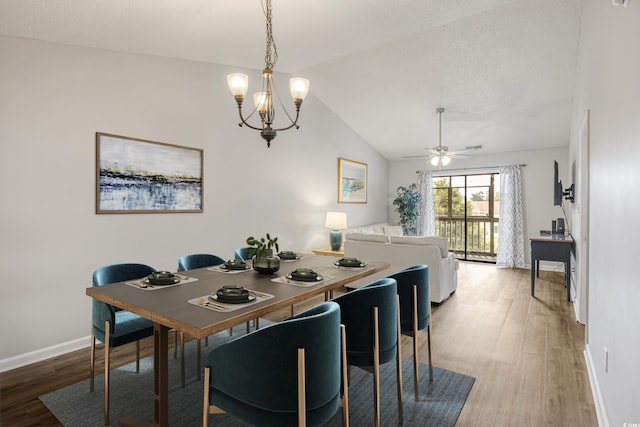 dining room featuring lofted ceiling, ceiling fan with notable chandelier, wood-type flooring, and a textured ceiling