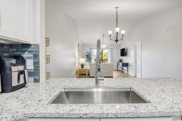 kitchen with light hardwood / wood-style flooring, sink, lofted ceiling, decorative backsplash, and a textured ceiling