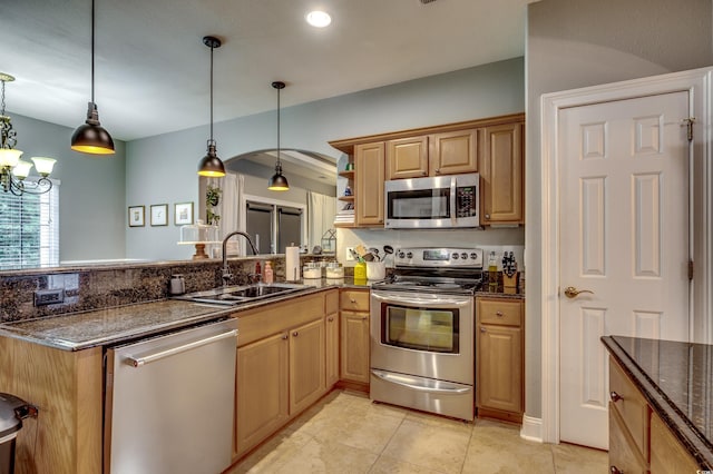 kitchen featuring kitchen peninsula, pendant lighting, stainless steel appliances, sink, and a chandelier