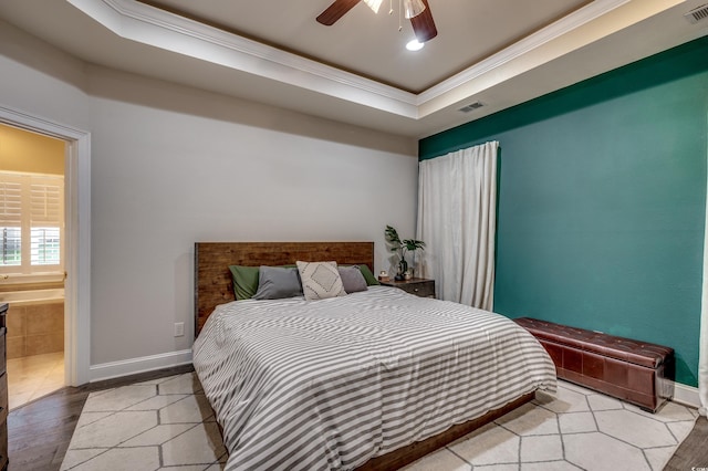 bedroom featuring a tray ceiling, ceiling fan, light hardwood / wood-style flooring, ornamental molding, and ensuite bath