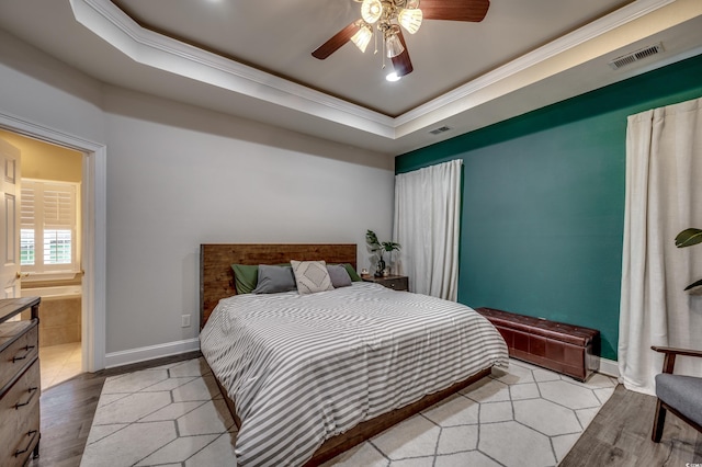 bedroom with light hardwood / wood-style flooring, a raised ceiling, ensuite bathroom, crown molding, and ceiling fan