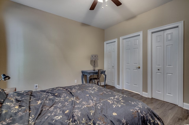 bedroom featuring ceiling fan, multiple closets, and dark hardwood / wood-style floors