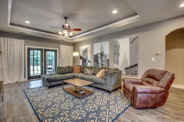 living room with ornamental molding, a tray ceiling, ceiling fan, and hardwood / wood-style floors