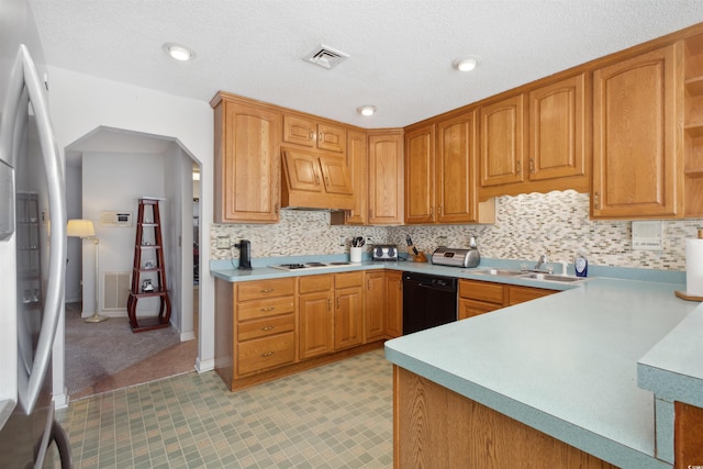 kitchen with a sink, visible vents, black dishwasher, light countertops, and stainless steel refrigerator