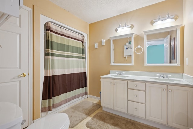 full bathroom with a textured ceiling, toilet, a shower with shower curtain, a sink, and double vanity