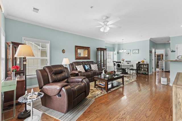 living room with ceiling fan with notable chandelier, ornamental molding, and hardwood / wood-style floors