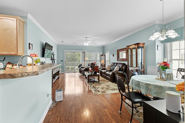 dining room with ceiling fan with notable chandelier, ornamental molding, dark wood-type flooring, and sink