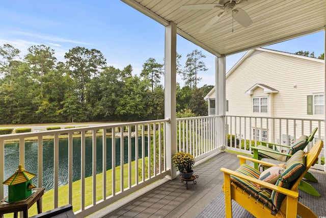 wooden deck featuring a lawn, a water view, and ceiling fan