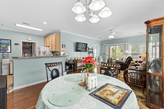 dining area with ceiling fan with notable chandelier, dark hardwood / wood-style floors, sink, and crown molding