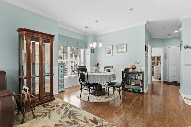 dining space featuring a textured ceiling, crown molding, an inviting chandelier, and hardwood / wood-style flooring