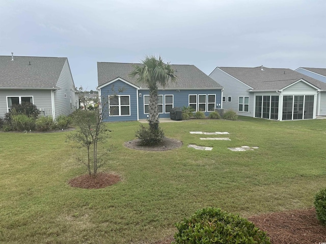 back of property with a sunroom and a lawn