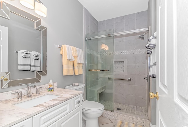 bathroom featuring vanity, toilet, tile patterned floors, and a shower with shower door