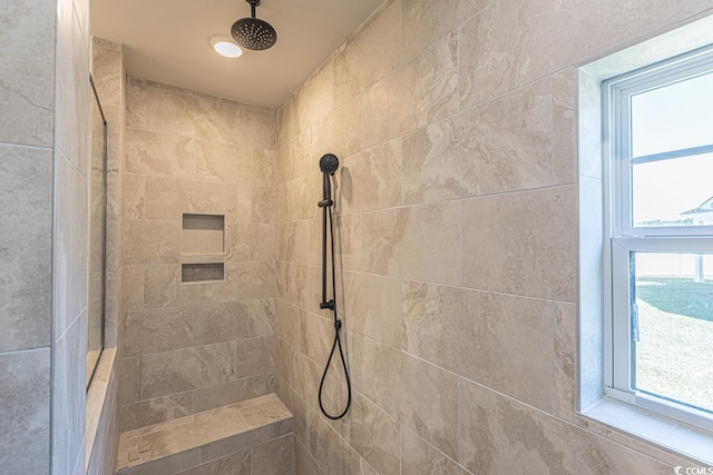 bathroom featuring a tile shower and a wealth of natural light