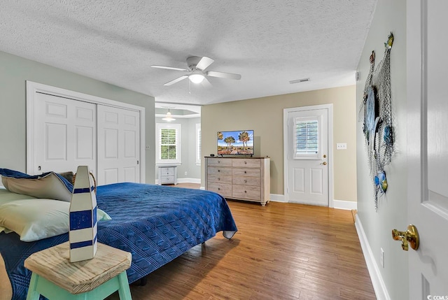 bedroom with a textured ceiling, wood-type flooring, ceiling fan, and a closet