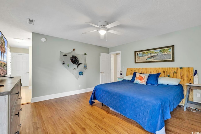 bedroom with ceiling fan, a textured ceiling, and hardwood / wood-style floors