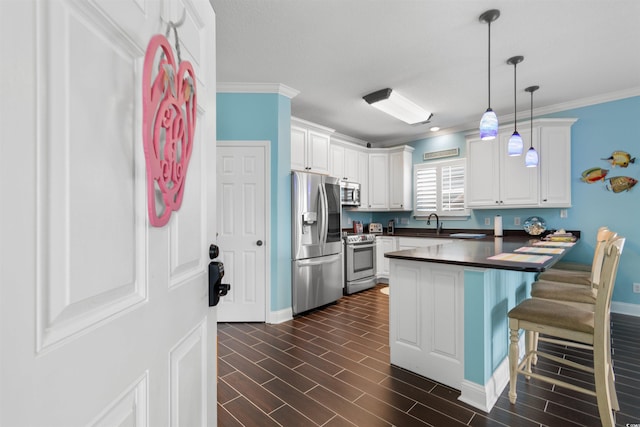 kitchen featuring white cabinets, a breakfast bar area, stainless steel appliances, and hanging light fixtures