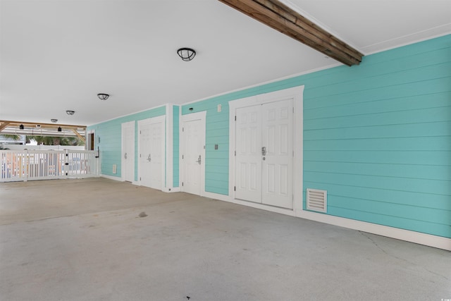 interior space with concrete floors, wood walls, and beamed ceiling