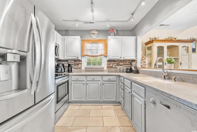 kitchen featuring tasteful backsplash, sink, appliances with stainless steel finishes, and light tile patterned flooring