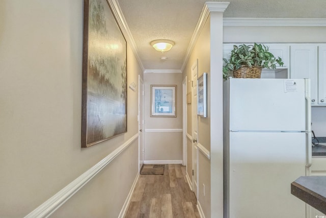 doorway featuring wood-type flooring, a textured ceiling, and crown molding