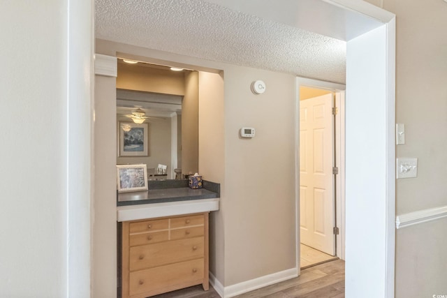 hallway with light hardwood / wood-style flooring and a textured ceiling