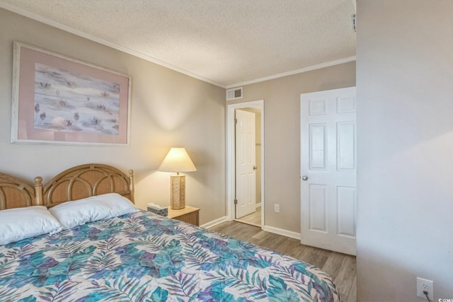 bedroom with light wood-type flooring, a textured ceiling, and ornamental molding