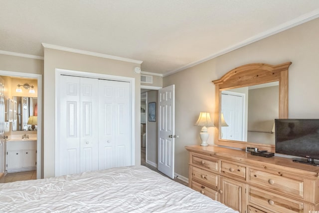 bedroom featuring connected bathroom, ornamental molding, sink, a textured ceiling, and a closet