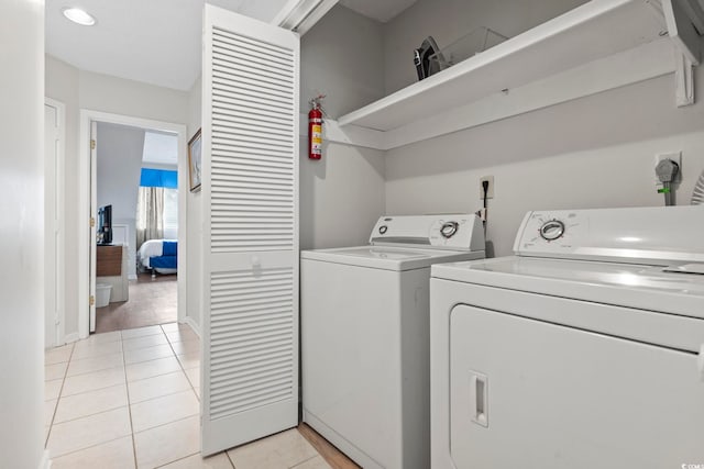 clothes washing area featuring light tile patterned flooring and washing machine and dryer